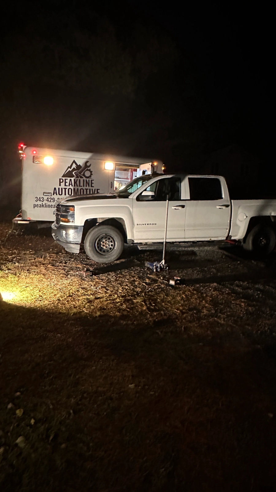 Working on a pickup after dark, lit by the service truck