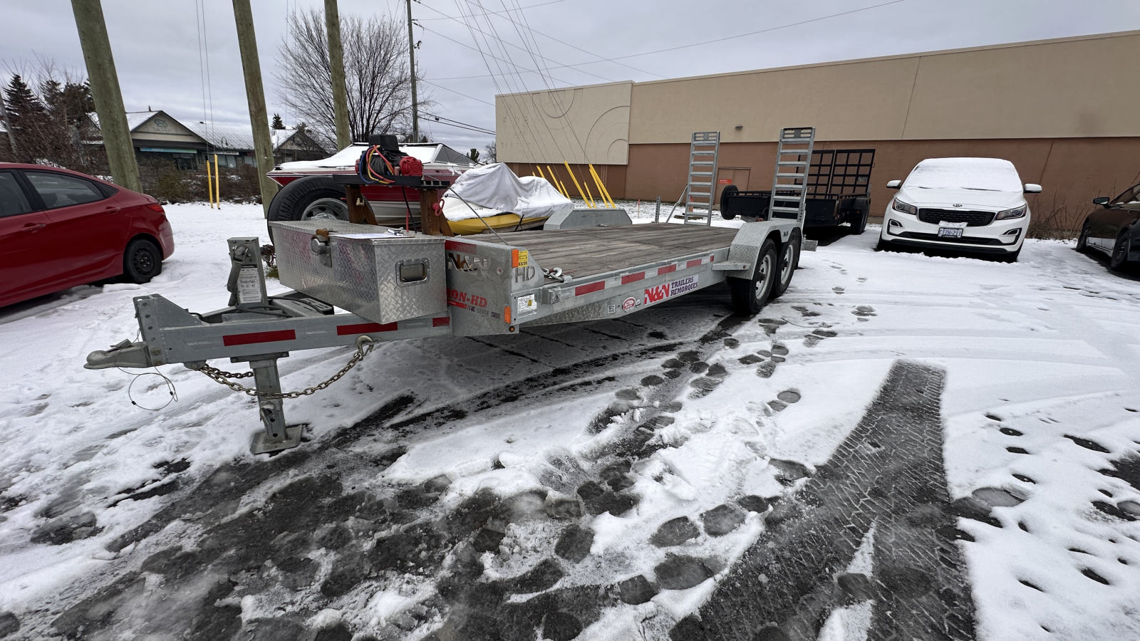 The 20 foot N&N galvanized equipment trailer side-on with its rear ramps stood up